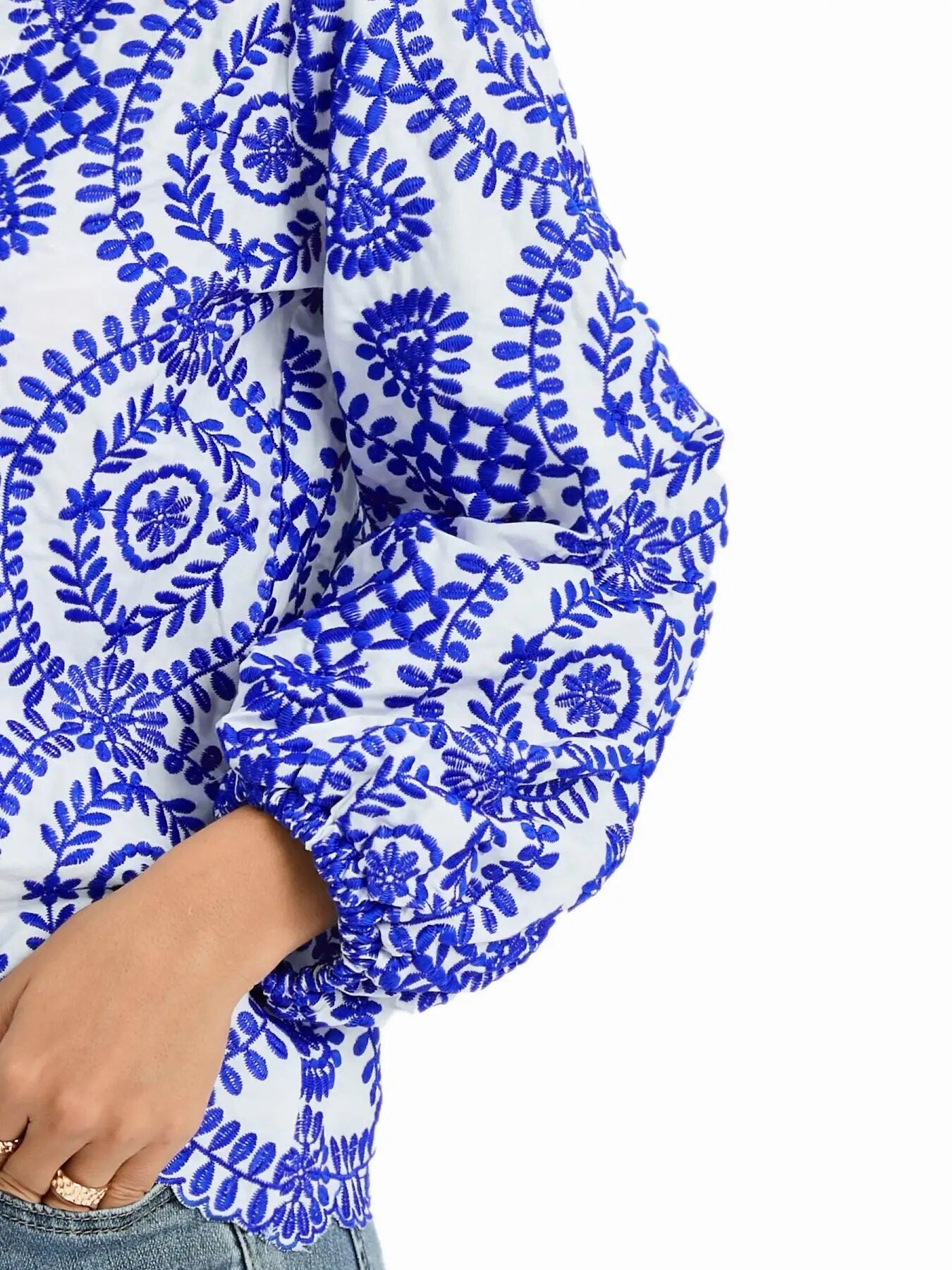 Weiße Bluse mit blauen Stickereien, florales Muster, lange Ärmel, traditioneller Bauernstil, modisch, handgefertigt, Damenbekleidung.