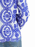 Weiße Bluse mit blauen Stickereien, floralen Mustern und langen Ärmeln. Perfekt für modische Outfits, Damenmode, Boho-Stil.