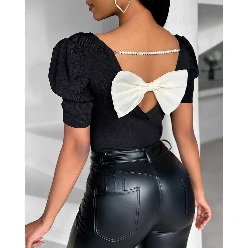 Schwarze Damenbluse mit Puffärmeln, Rückenausschnitt und weißer Schleife. Elegantes Design, ideal für Casual- und Abendmode.