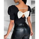 Schwarze Damenbluse mit Puffärmeln, Rückenausschnitt und weißer Schleife. Elegantes Design, ideal für Casual- und Abendmode.