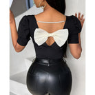 Schwarze Damenbluse mit Puffärmeln, rundem Ausschnitt und Rückendekor aus Schleife und Perlen. Elegante, modische Oberbekleidung.