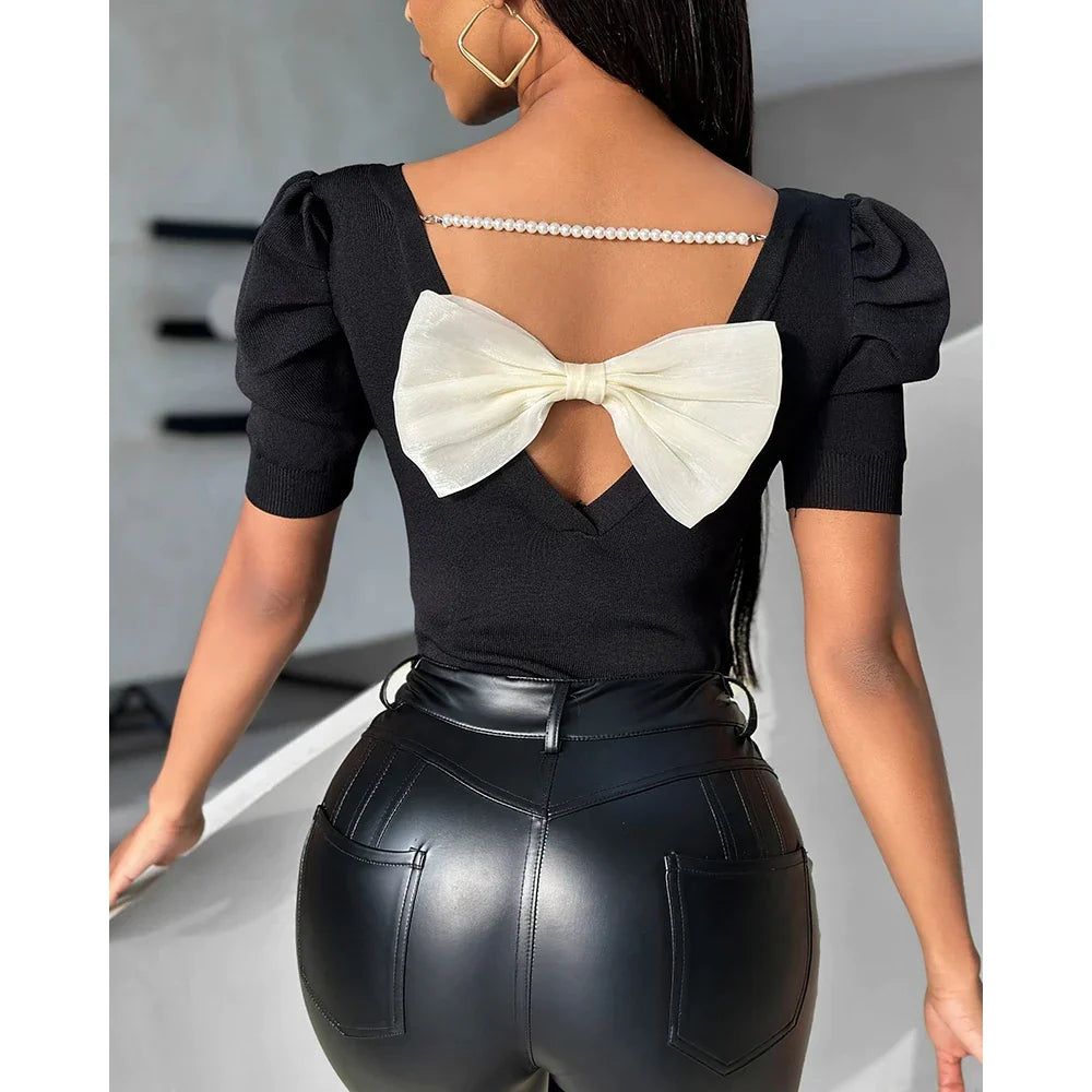 Schwarze Damenbluse mit Puffärmeln, Rückenausschnitt und weißer Schleife. Perfekt für elegante Anlässe. Modische, stilvolle Oberbekleidung.