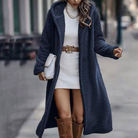Frau in elegantem, blauem Teddy-Mantel, weißem Strickkleid und braunen Stiefeln. Modetrend Herbst/Winter, stilvoller Streetstyle-Look.