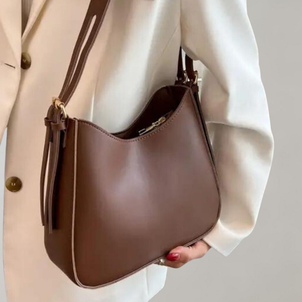 Elegante braune Lederhandtasche mit goldenen Details, ideal für Damenmode. Perfekt für stilvolle Outfits und zeitlose Eleganz.