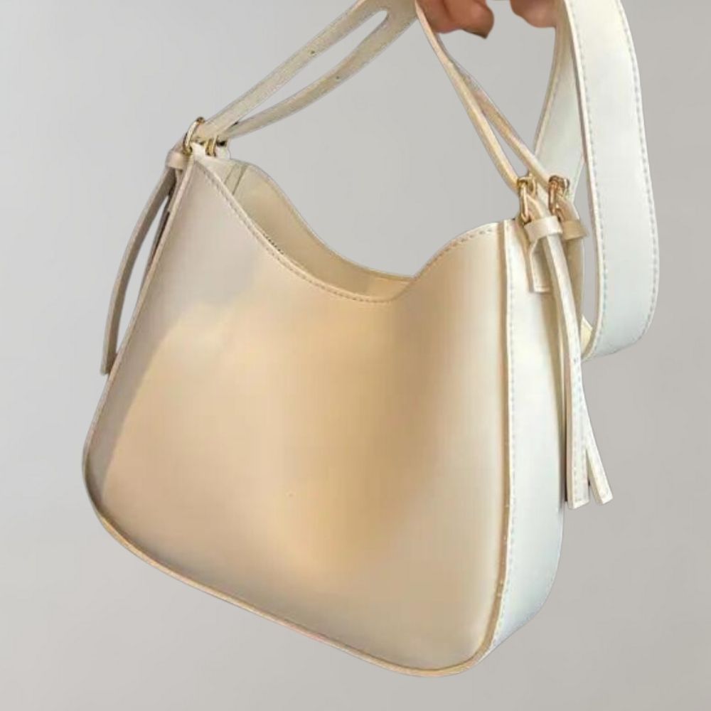Elegante cremeweiße Handtasche aus Leder mit goldenen Details und verstellbarem Riemen. Perfekt für Damenmode und stilvolle Outfits.
