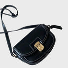Elegante schwarze Umhängetasche aus Leder mit goldener Schnalle und verstellbarem Riemen. Perfekt für Damenmode und Accessoires.