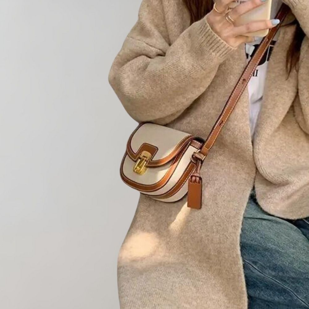 Damenhandtasche aus Leder in Beige mit braunen Akzenten, verstellbarem Schulterriemen und goldener Schnalle. Perfekt für stilvolle Alltagslooks.
