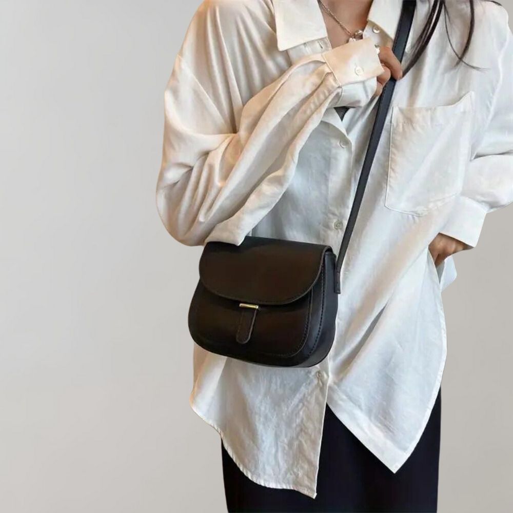 Schwarze Leder-Umhängetasche, elegant und zeitlos, kombiniert mit weißer Bluse. Perfekt für Damenmode, Accessoires, stilvolle Outfits.