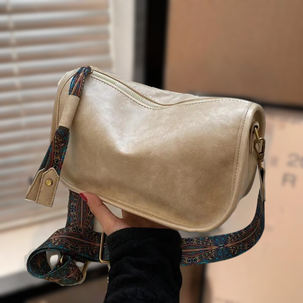 Beige Umhängetasche aus Leder mit verstellbarem, gemustertem Schultergurt. Stilvoll und praktisch für den täglichen Gebrauch.
