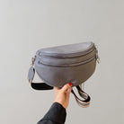 Graue Leder-Bauchtasche mit verstellbarem Riemen und Reißverschlüssen, ideal für stilvolle Aufbewahrung und praktischen Alltagsgebrauch.