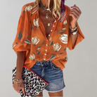 Frau in orangefarbener Blumenbluse, Jeansshorts, Leoparden-Clutch, modisch, lässig.