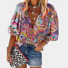Frau in bunter Paisley-Bluse und Jeansrock, hält Leoparden-Clutch, modisch, sommerlich.