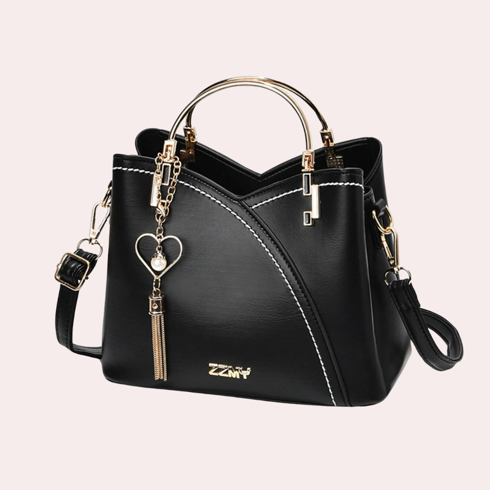 Elegante schwarze Handtasche mit goldenen Akzenten, Herzanhänger und verstellbarem Schulterriemen. Perfekt für Damenmode und Accessoires.