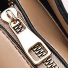 Nahaufnahme eines goldenen Reißverschlusses an einer khakifarbenen Tasche. Hochwertiges Accessoire, modisch, langlebig, stilvolles Design.