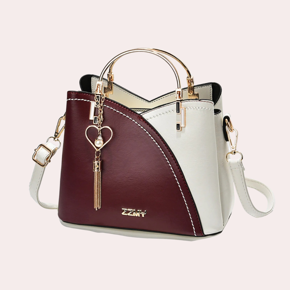 Elegante zweifarbige Handtasche in Weinrot und Weiß mit goldenen Akzenten und Herzanhänger. Perfekt für stilvolle Damenmode und Accessoires.