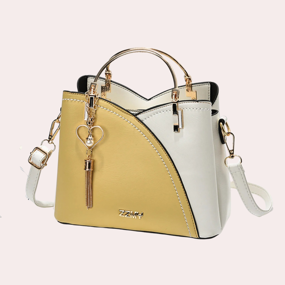 Elegante zweifarbige Handtasche in Gelb und Weiß mit goldenen Akzenten und Herzanhänger. Perfekt für stilvolle Damenmode und Accessoires.
