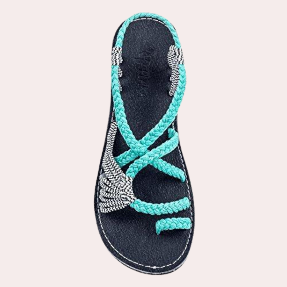 Handgefertigte Sandale mit türkisfarbenen, geflochtenen Riemen und Perlendetails auf schwarzer Sohle. Perfekt für Sommermode und Strandoutfits.