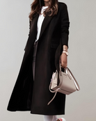 Eleganter schwarzer Mantel für Damen, kombiniert mit weißem Oberteil und beiger Handtasche. Perfekt für stilvolle Herbst- und Wintermode.
