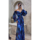 Frau in blauem, schulterfreiem Abendkleid mit langen Ärmeln, elegantes Design, modisch.
