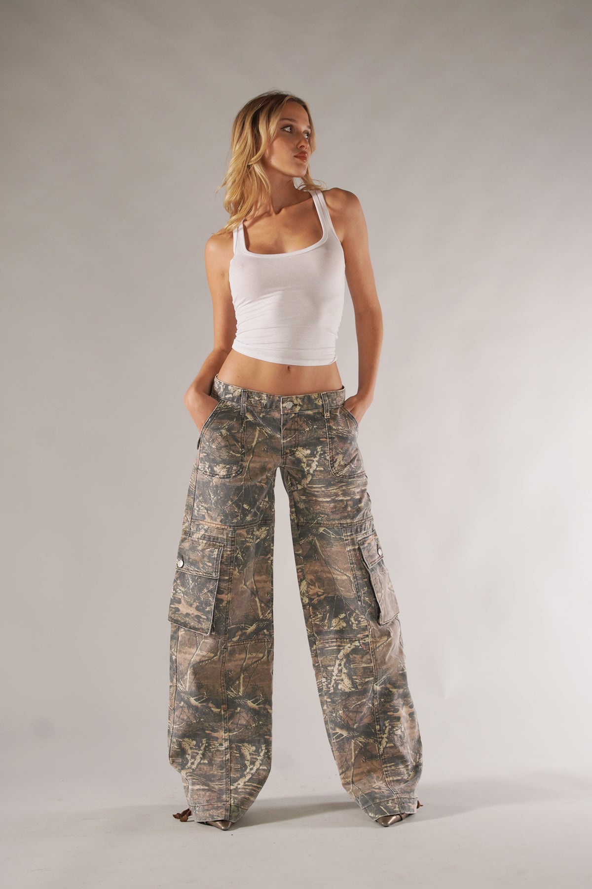 Frau in weißem Tanktop und Camouflage-Cargohose. Modetrend, lässiger Stil, Damenbekleidung, urbaner Look, Freizeitmode, Streetwear.