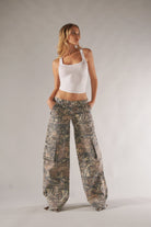 Frau in weißem Tanktop und Camouflage-Cargohose. Modetrend, lässiger Stil, Damenbekleidung, urbaner Look, Freizeitmode, Streetwear.