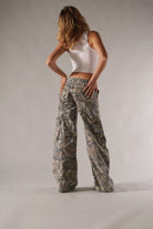 Frau in weißem Tanktop und Camouflage-Cargohose, modisch und lässig. Perfekt für Streetwear, Outdoor-Abenteuer und trendige Freizeitlooks.