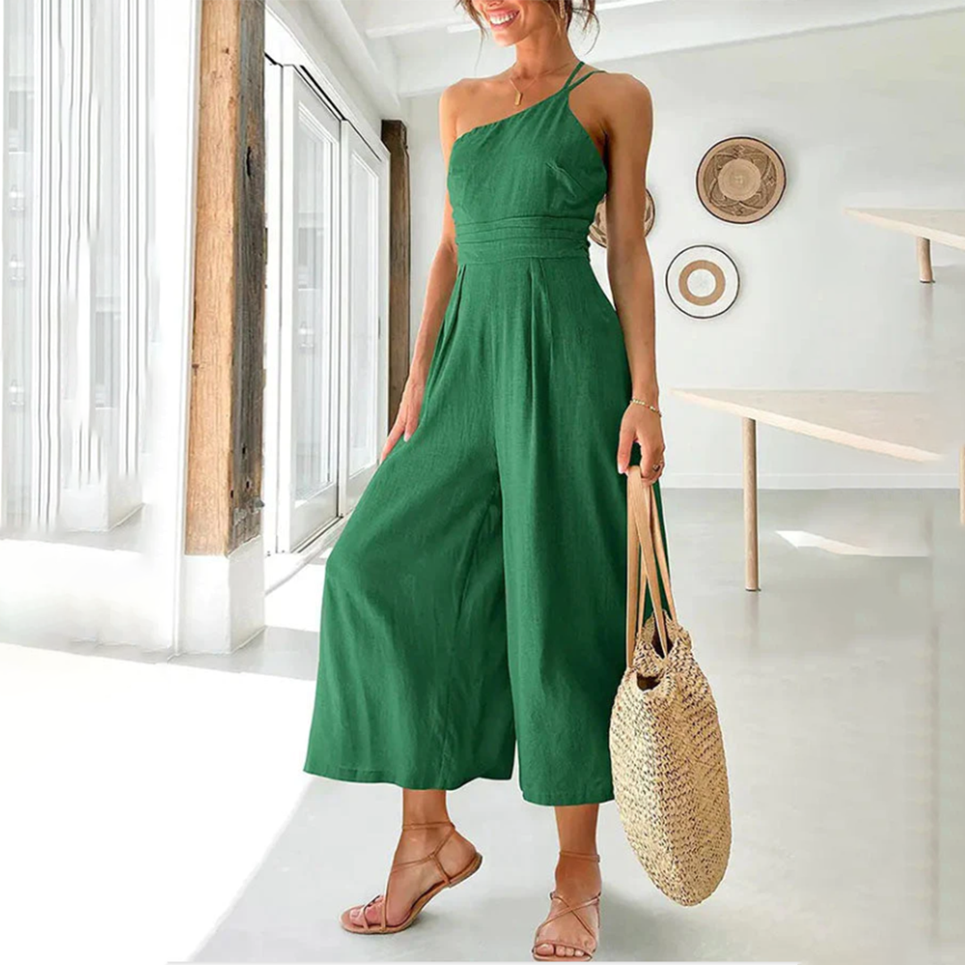 Frau in dunkelgrünem Jumpsuit, Sommermode, Strohtasche, elegantes Design, helle Umgebung.
