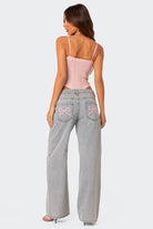 Frau in rosa Top und weiten Jeans mit Schleifenstickerei, modisch und lässig. Perfekt für trendige Streetwear und Sommermode.