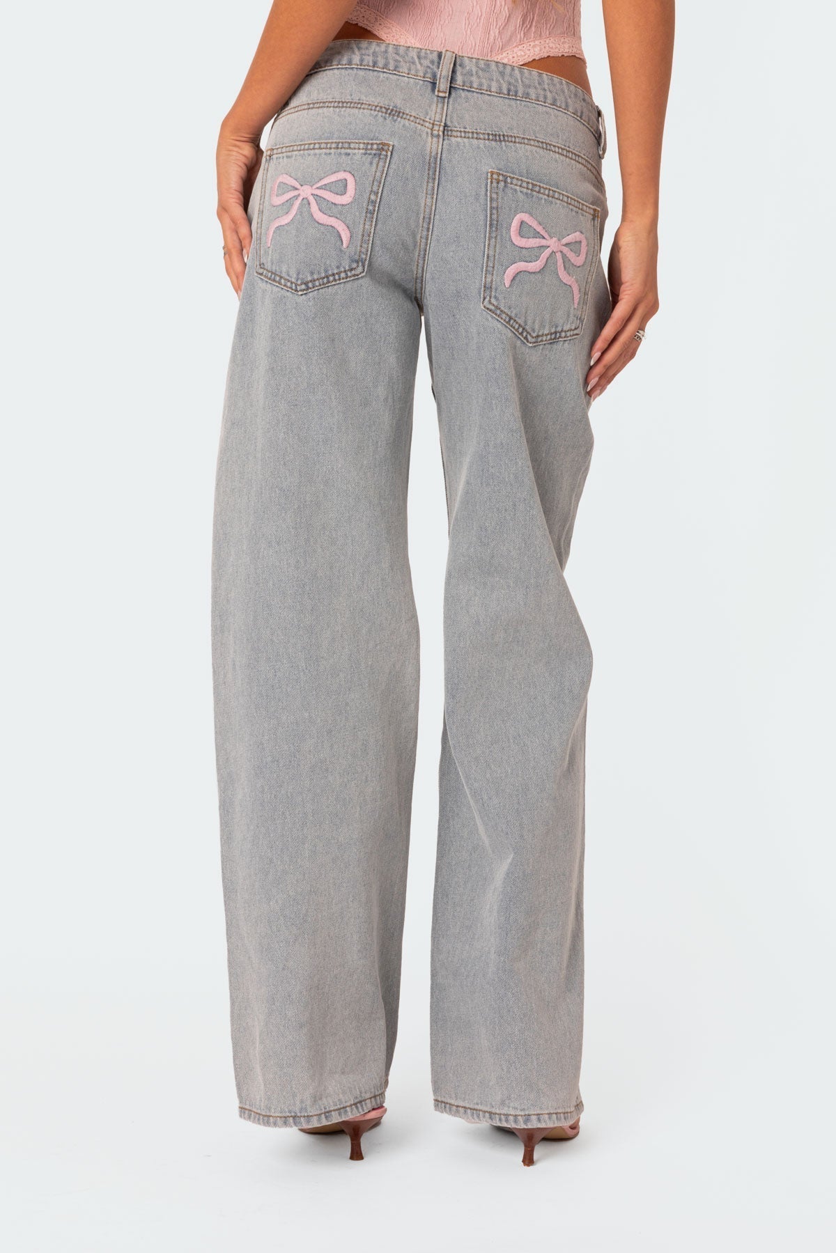 Damen-Jeans mit weitem Bein, grauer Waschung und rosa Schleifenstickerei auf den Gesäßtaschen. Modetrend, lässiger Stil, Streetwear.
