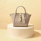 Elegante graue Handtasche aus Leder mit goldenen Details, ideal für Damenmode. Perfekt für stilvolle Auftritte und modische Accessoires.