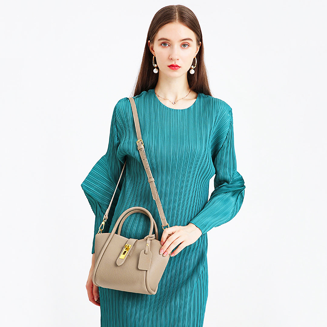 Frau mit eleganter, beiger Handtasche und grünes Kleid. Modetrend, Accessoire, Damenmode, stilvoll, modern, Handtaschen, Modefotografie.