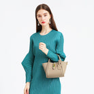 Frau in elegantem, grünem Kleid hält stilvolle, beige Handtasche. Mode, Damenbekleidung, Accessoires, elegantes Design, trendige Handtaschen.