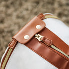 Weiße Reisetasche mit braunen Lederakzenten und Reißverschluss, faltbar, stilvoll, langlebig.