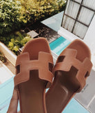 Braune Ledersandalen mit H-Design, ideal für Sommermode. Hochwertige Materialien, stilvoll und bequem. Perfekt für den Strand oder die Stadt.