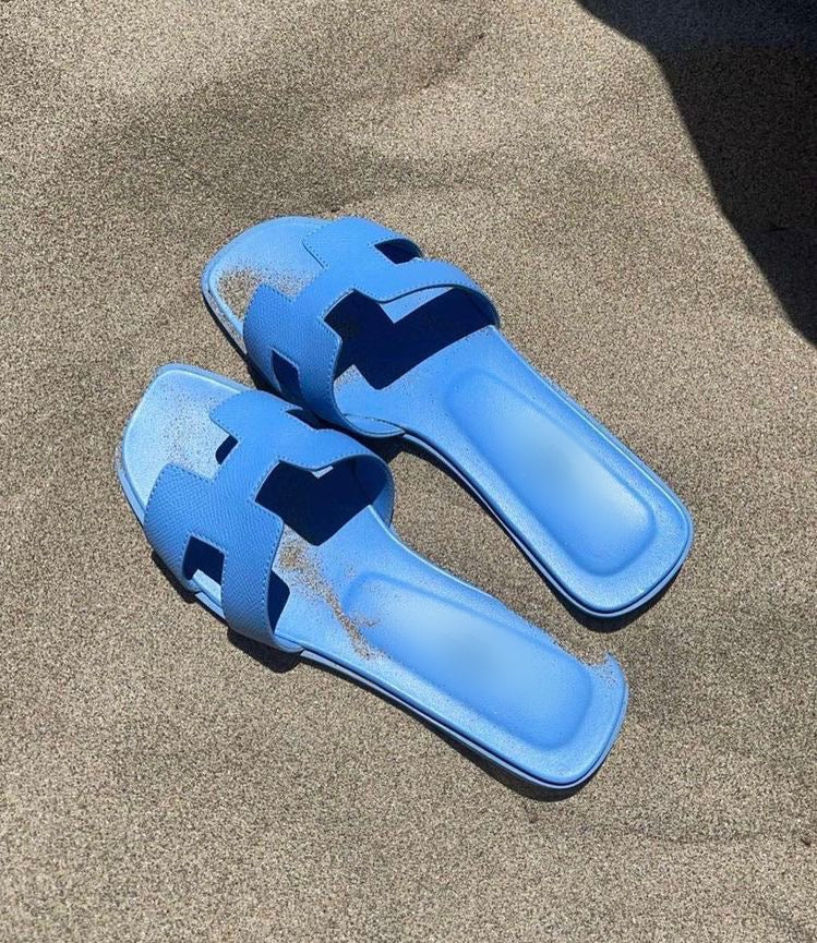 Blaue Sandalen auf Sand, ideal für den Strand. Bequeme Sommerschuhe, modisch und strapazierfähig. Perfekt für Urlaub und Freizeit.