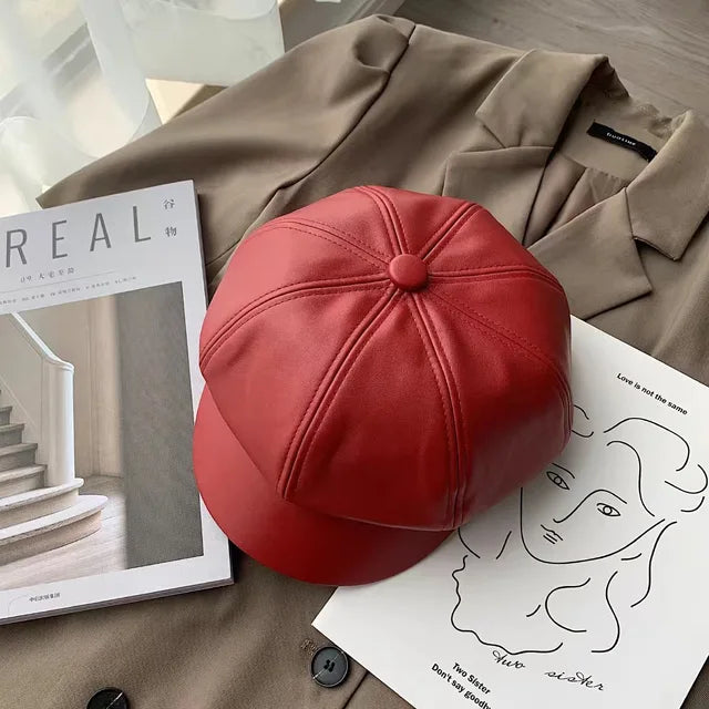 Rote Leder-Newsboy-Mütze auf braunem Mantel, stilvoll und modern. Perfekt für Herbst und Winter. Keywords: Leder, Mütze, Newsboy, Mode, Damen.