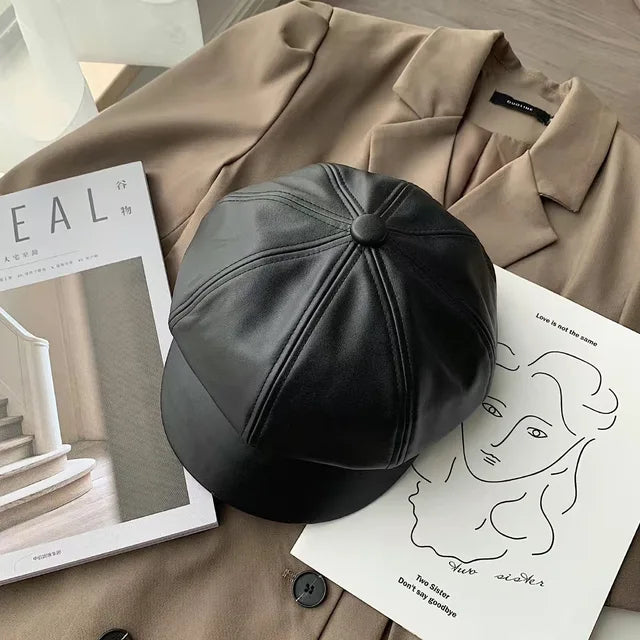 Schwarze Leder-Newsboy-Mütze auf beigem Mantel, stilvoll und modern. Perfekt für Herbst und Winter. Trendige Damenmode, koreanischer Stil.