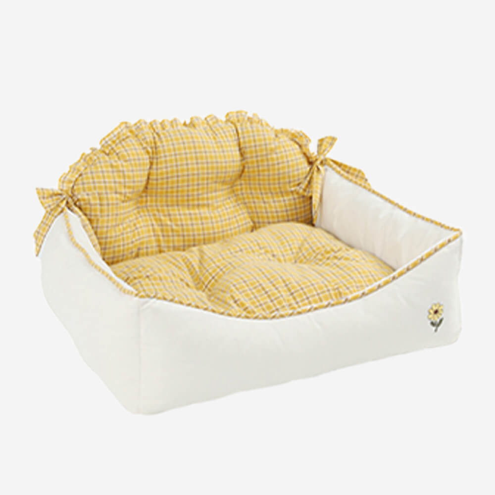 Gelbes kariertes Katzenbett, weiches Material, dekorative Schleifen, gemütlicher Schlafplatz.