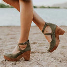 Grüne Damen-Clogs mit Holzabsatz am Strand. Modische, bequeme Schuhe für Sommer und Freizeit. Perfekt für stilvolle Outfits und Strandspaziergänge.