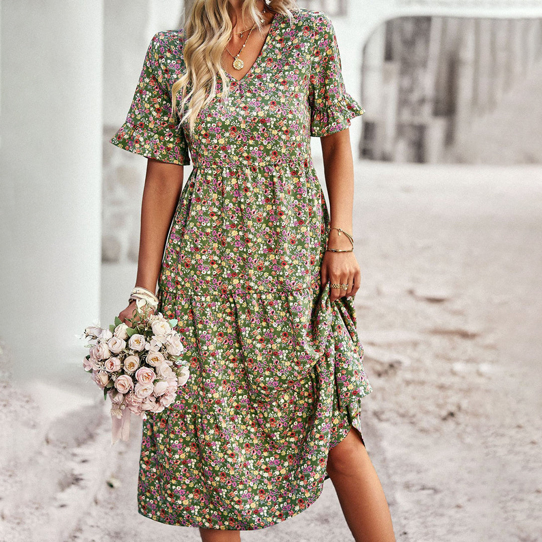 Frau in geblümtem Sommerkleid hält Blumenstrauß, ideal für Boho-Mode, Vintage-Look, romantische Outfits. Perfekt für Frühlings- und Sommertrends.