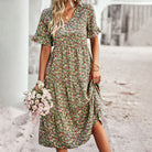 Frau in geblümtem Sommerkleid hält Blumenstrauß, ideal für Boho-Mode, Vintage-Look, romantische Outfits. Perfekt für Frühlings- und Sommertrends.