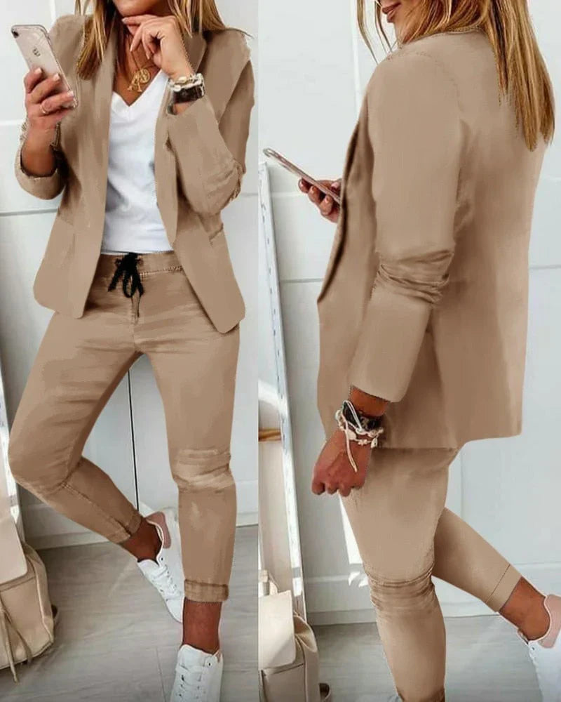 Beige Damenanzug mit Blazer und Hose, kombiniert mit weißem T-Shirt und Sneakers. Modischer Business-Look, ideal für Büro und Freizeit.