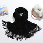 Schwarzer Schal mit Fransen aus weichem Material, ideal für Herbst und Winter. Modisches Accessoire, vielseitig kombinierbar, zeitloses Design.