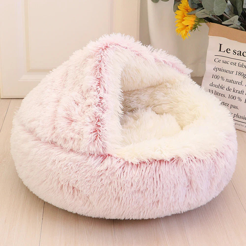 Rosa flauschiges Katzenbett aus Kunstfell, rund, gemütlich, für Haustiere, auf Holzboden.