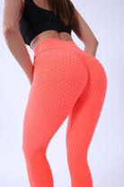 Frau in neonorange Textur-Leggings und schwarzem Top, Sportbekleidung, Fitnessmode.