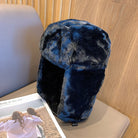 Kuschelige, blaue Kunstpelz-Fliegermütze auf einem Sofa. Wintermode, warme Kopfbedeckung, stilvoller Schutz vor Kälte. Ideal für kalte Tage.