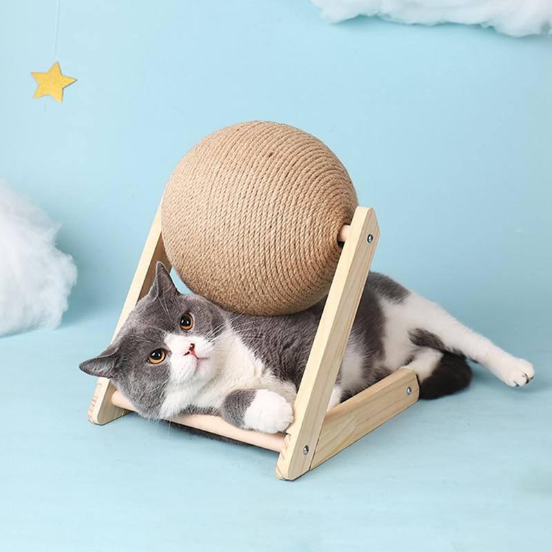 Graue Katze mit Kratzball aus Sisal auf Holzrahmen, Spielzeug für Katzen, vor blauem Hintergrund.
