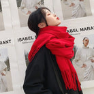 Frau mit rotem Schal vor Isabel Marant Plakaten. Modetrend, Winteraccessoire, stilvoller Look, Streetstyle, Modefotografie.