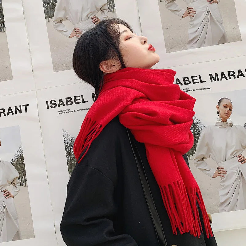 Frau mit rotem Schal vor Isabel Marant Plakaten. Modetrend, Winteraccessoire, stilvoller Look, Streetstyle, Modefotografie.
