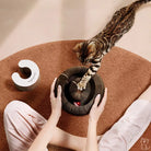 Katze spielt mit interaktivem Katzenspielzeug auf braunem Teppich, modernes Design, Unterhaltung.